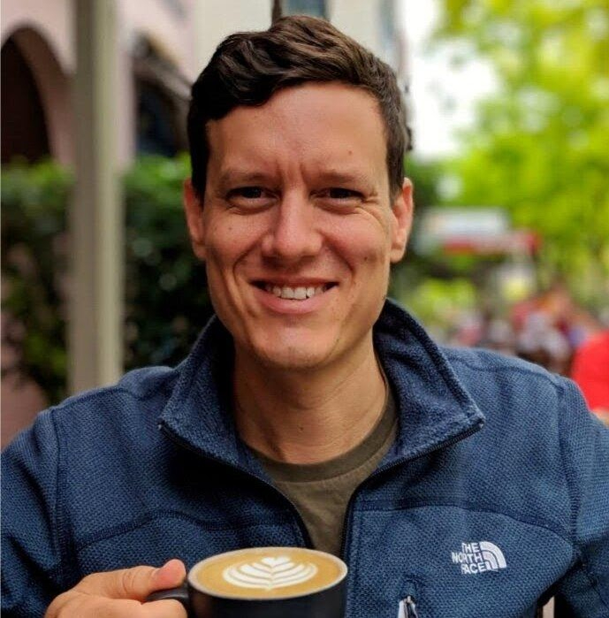 Henk smiling, holding a latte
